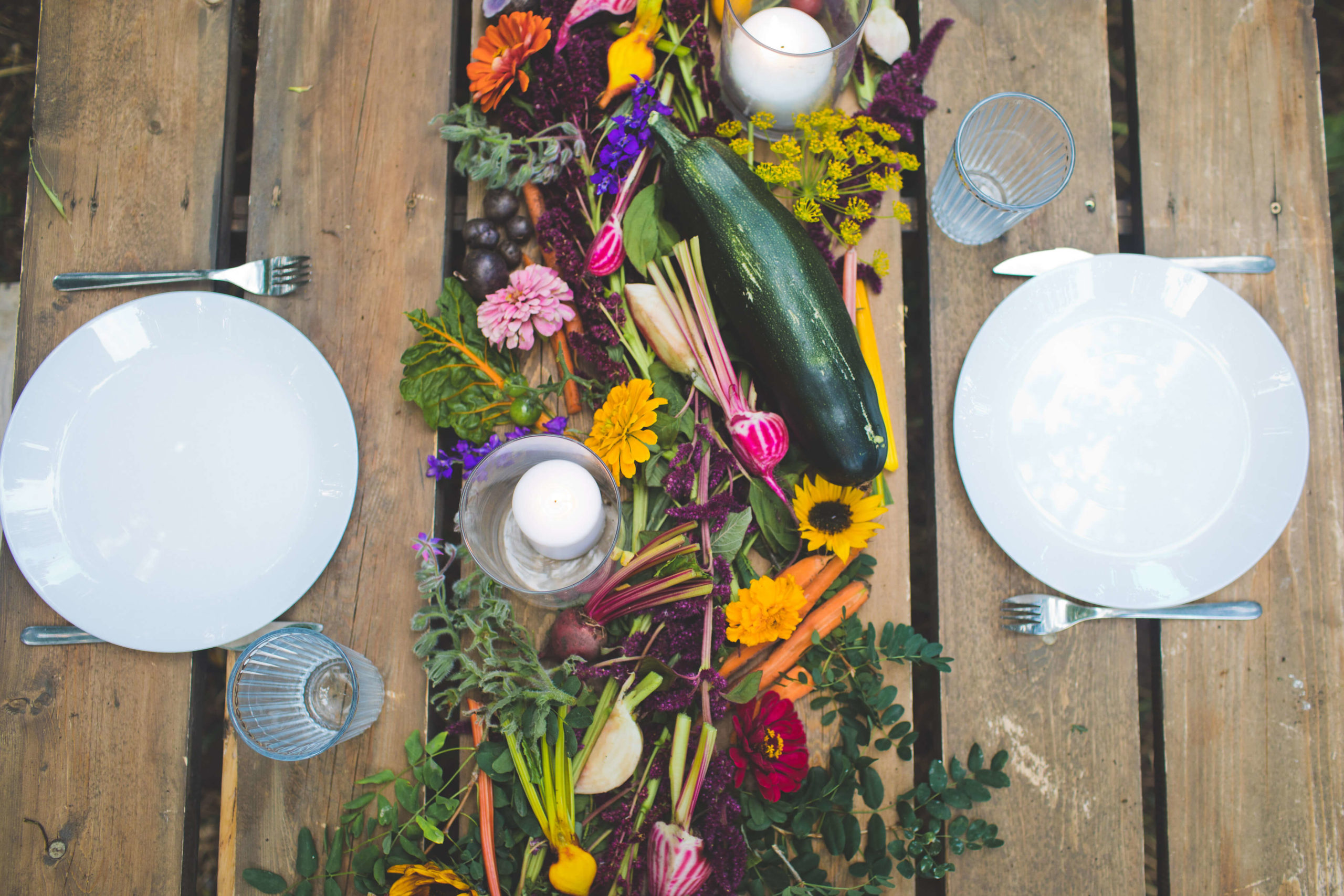 A farm to table food experience featuring a table set with plates and locally sourced vegetables on a wooden table.