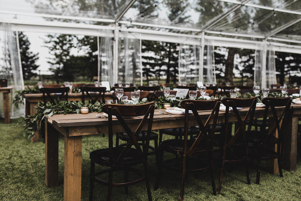 clear tent wedding venue with wood tables. https://www.thegathered.ca