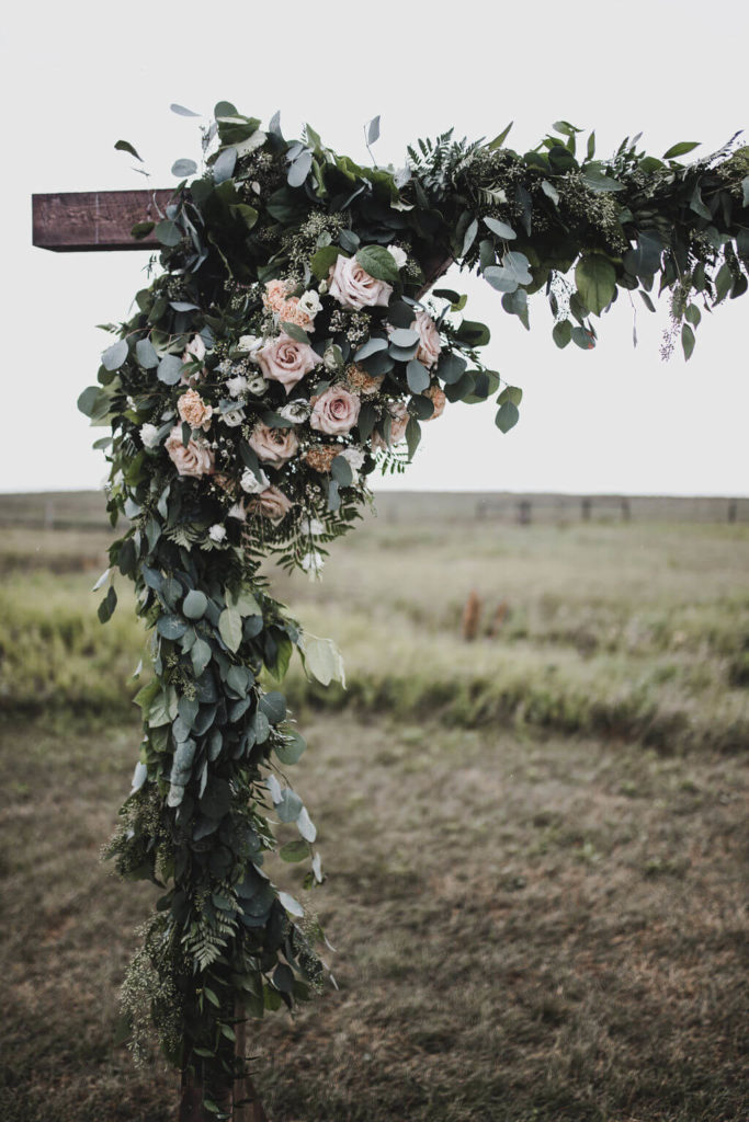 mix of greenery and flowers on a wood ceremony arch https://www.thegathered.ca