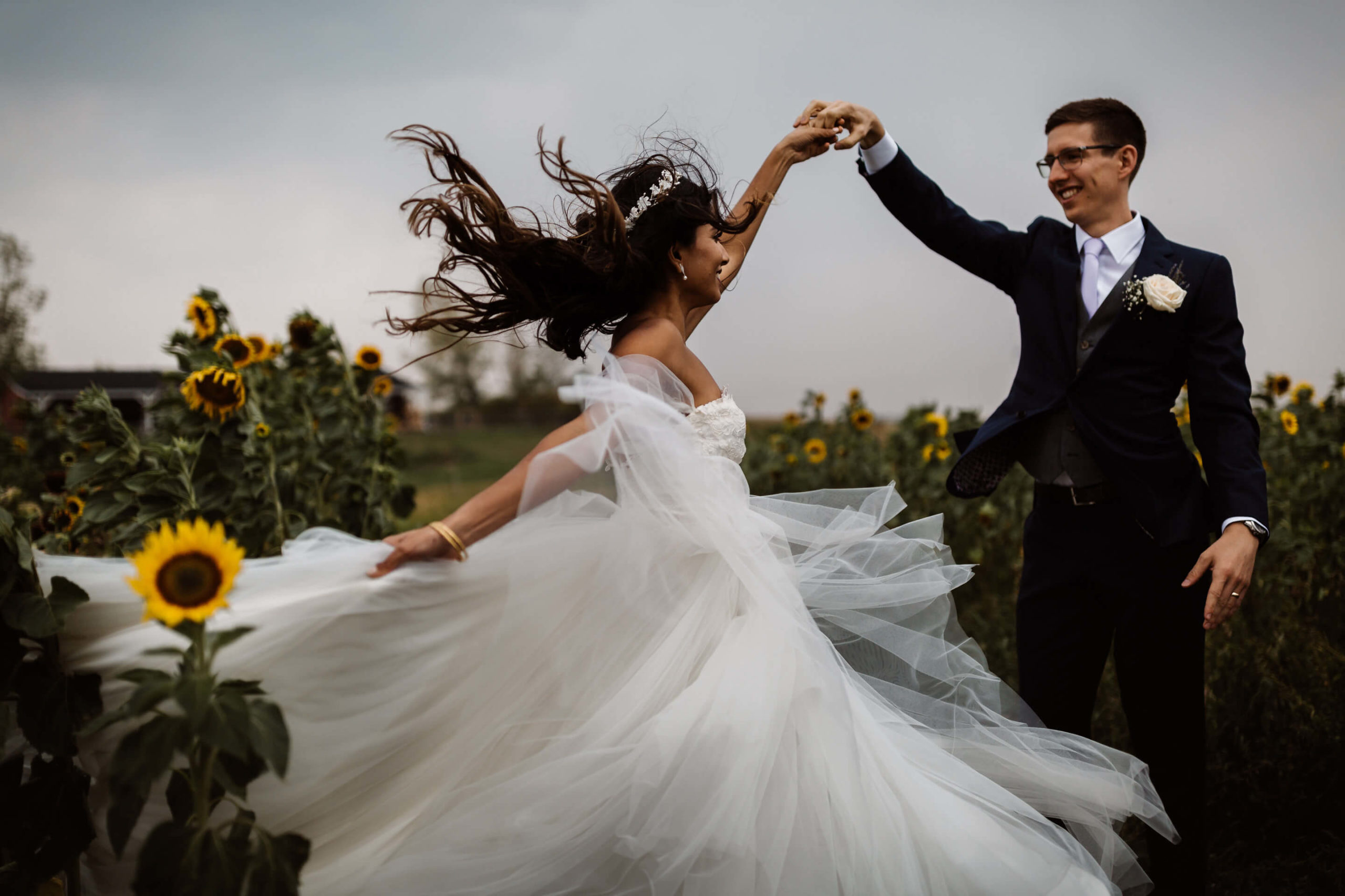 A bride and groom dancing in a field of sunflowers.