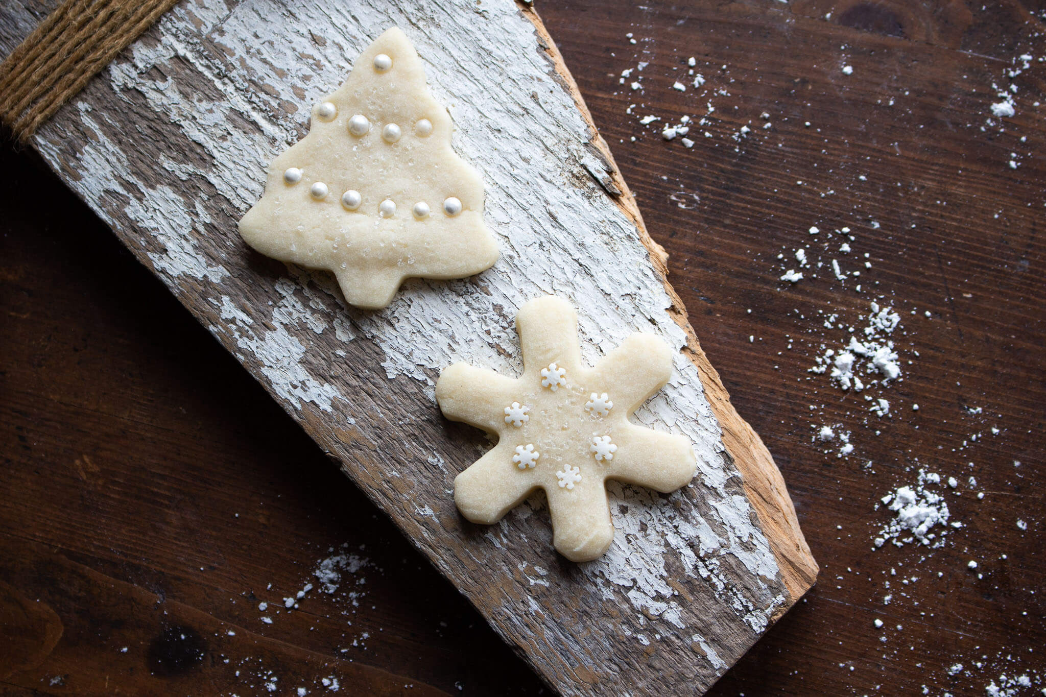 Two of the best sugar cookies on a wooden cutting board.