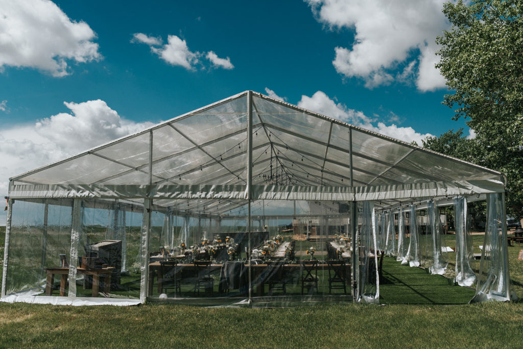 outside view of a transparent tent with wood tables and bright blue skies