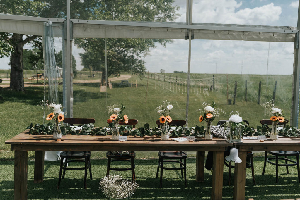 wedding head table in a clear tent and decorated with sunflower centrepieces 