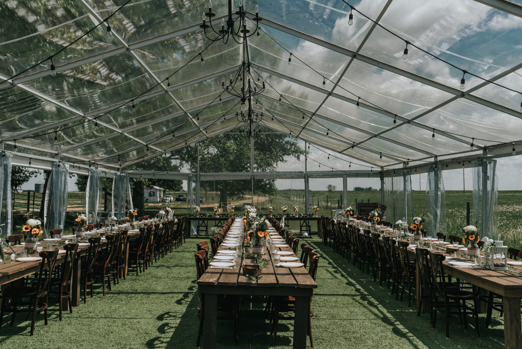 inside view of the clear tent with 3 rows of wood tables