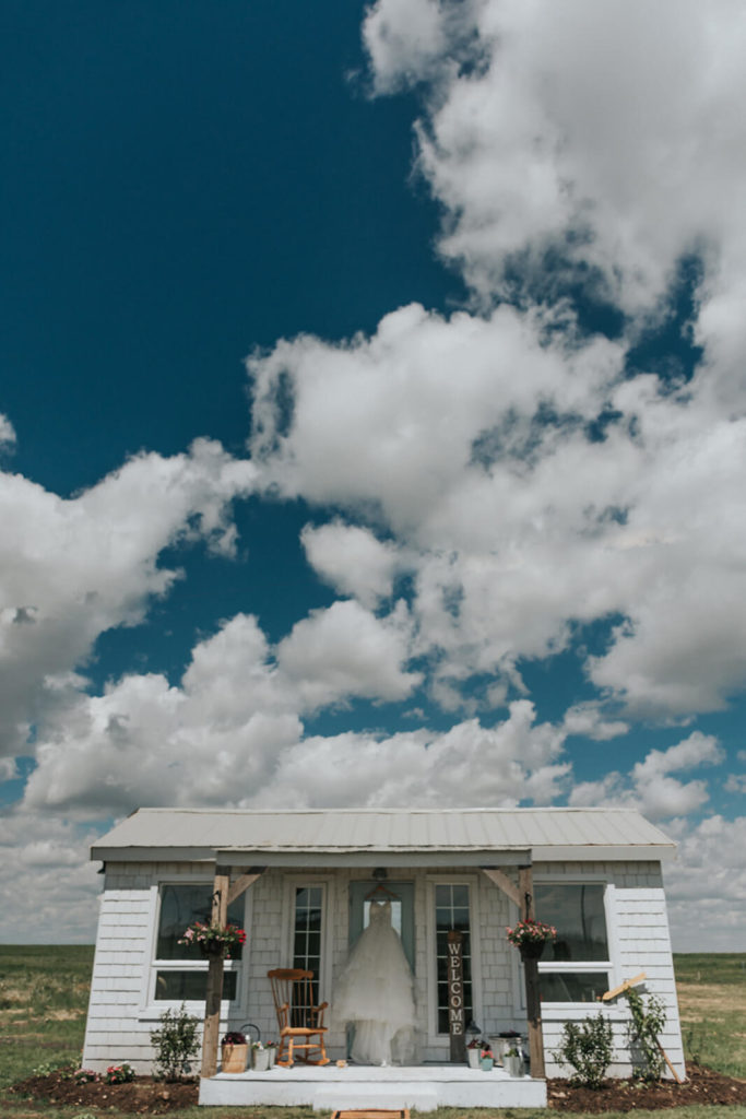 little white cottage with a blue sky backdrop and big fluffy clouds