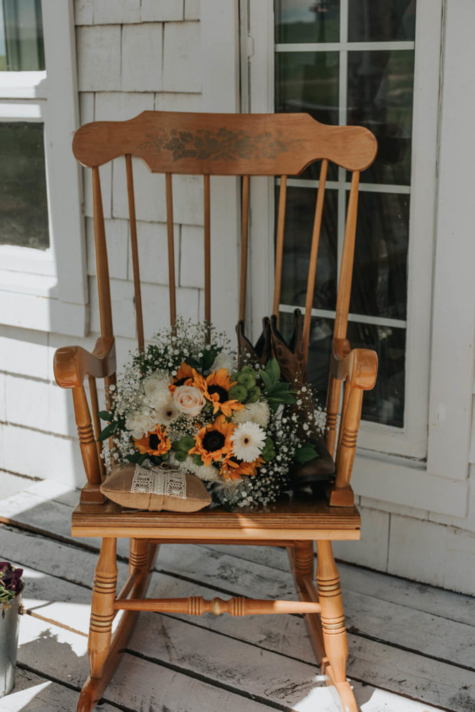 a rocking chair on a front porch with a sunflower bouquet sitting on it