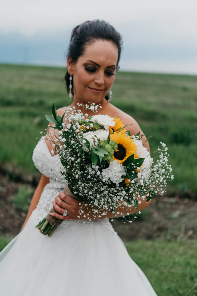bride in a white dress holding her sunflower bouquet 