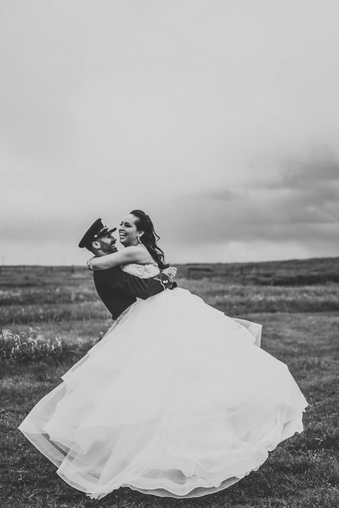black and white image of groom lifting bride and twirling 