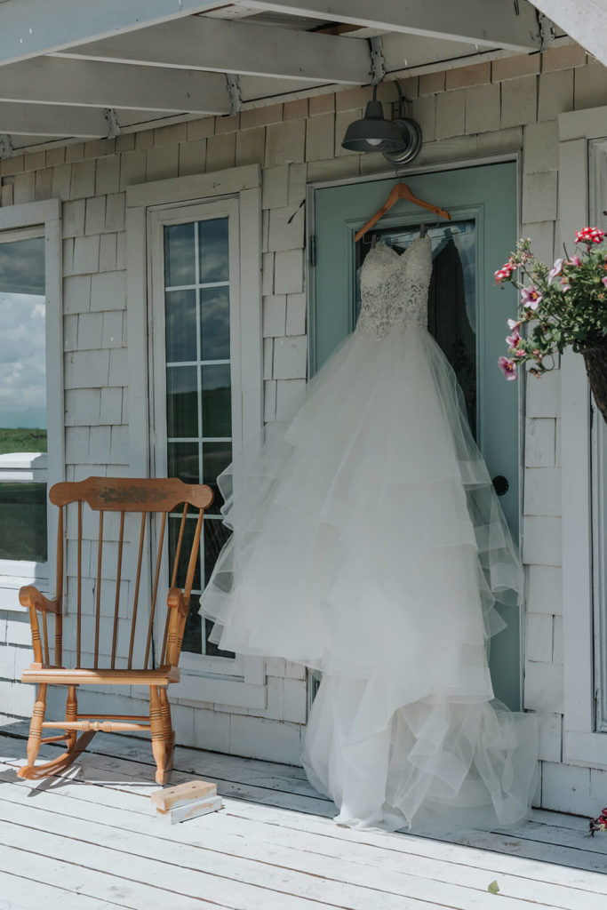 wedding dress hanging on the outside of a white cottage on the blue door 