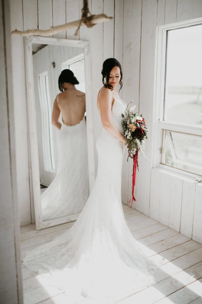 bride standing in an all white cottage while her dress fans out around her