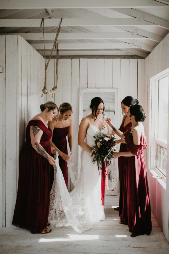 four bridesmaids wearing dark red dresses surrounding the bride