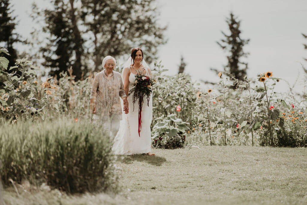 bride walking down a flower path with her grandma
