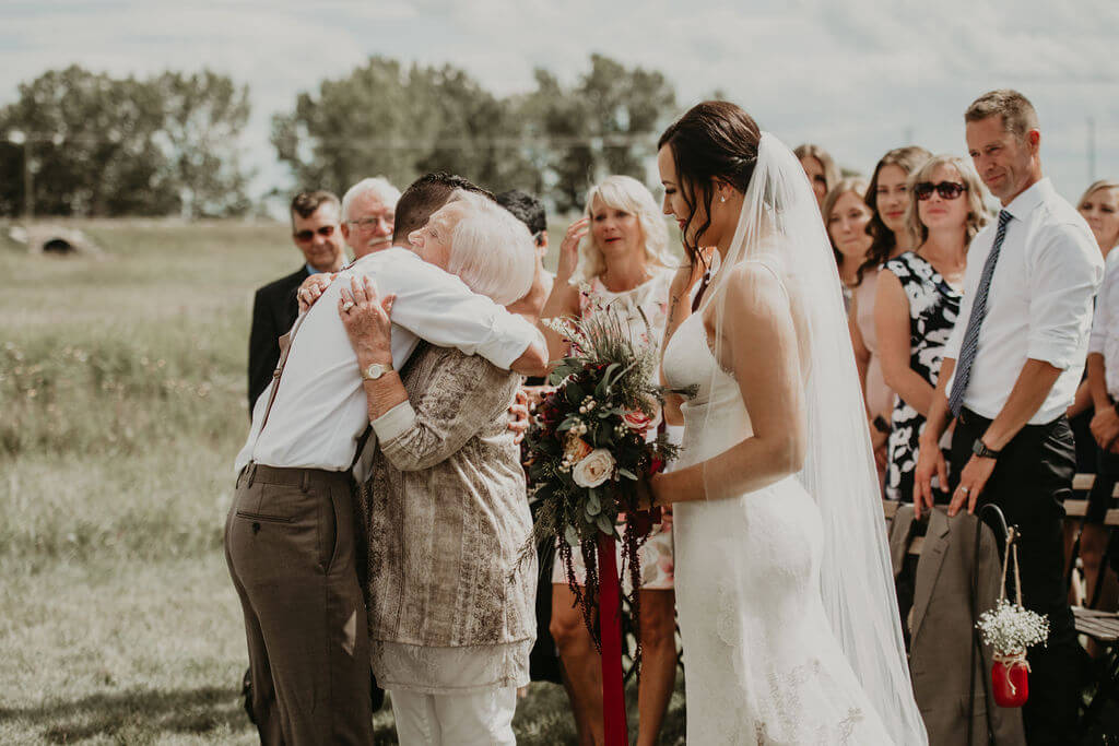 grandma hugging the groom and the front of the ceremony alter