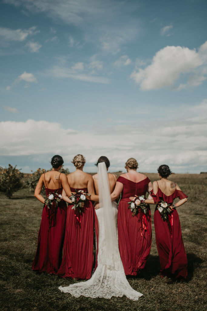 backside of four bridesmaids in red dresses and the bride in the middle