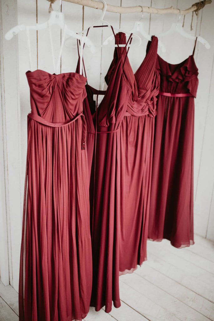 four red dresses hanging on hangers in a white cottage