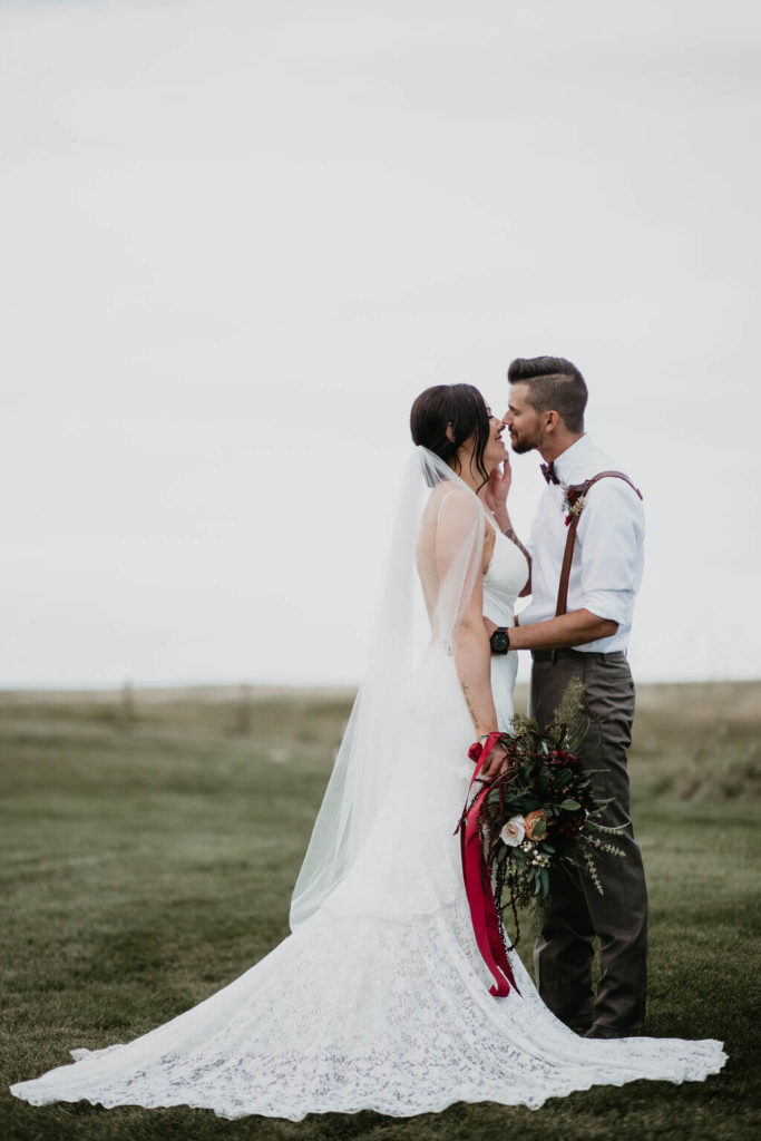 bride and groom almost kissing standing in an open prairie field
