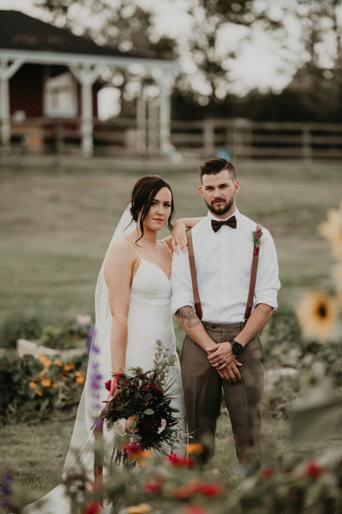 bride and groom standing around a garden of flowers