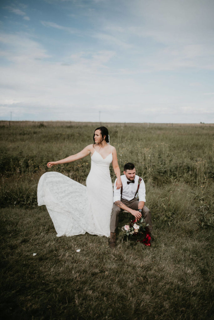 bride and groom sitting in a open prairie field surrounded by lush green grass