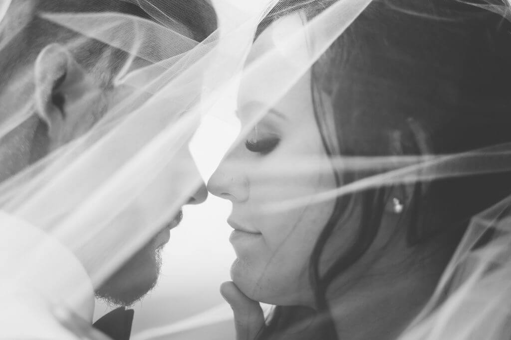 black and white photo of couple under the brides veil