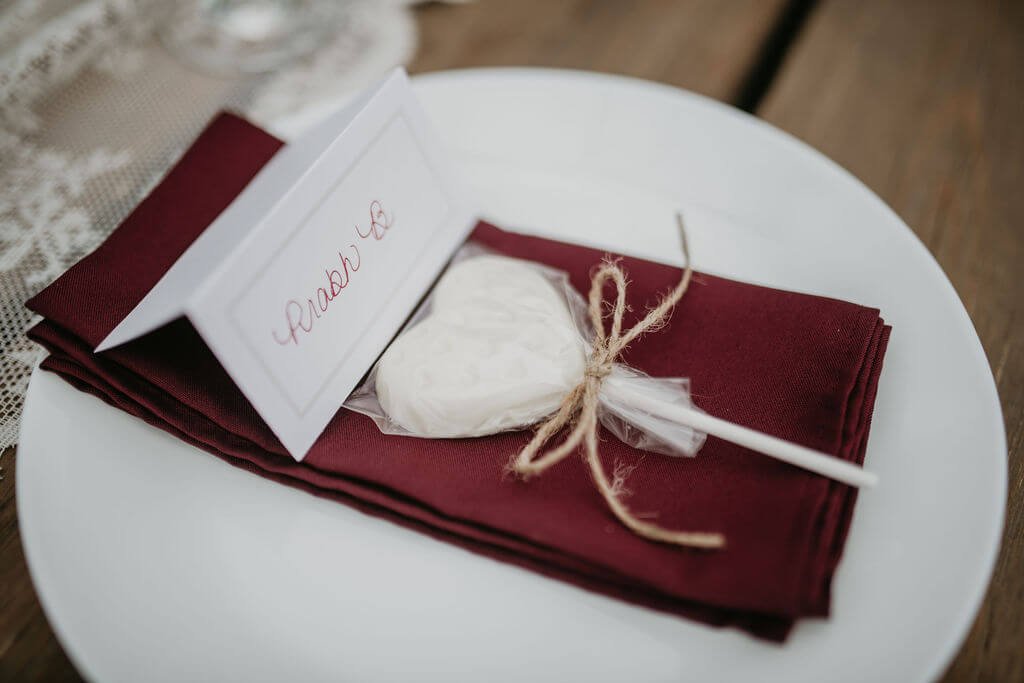 place setting with a white plate, burgundy decor and little name tags