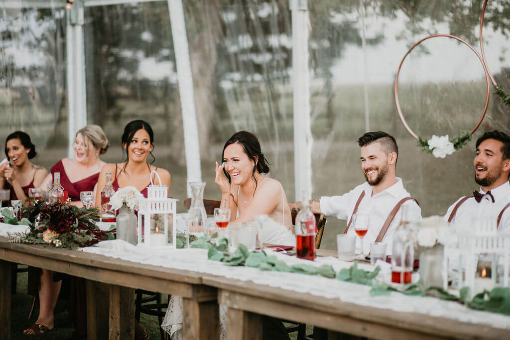 wedding head table with bridal party laughing at speeches