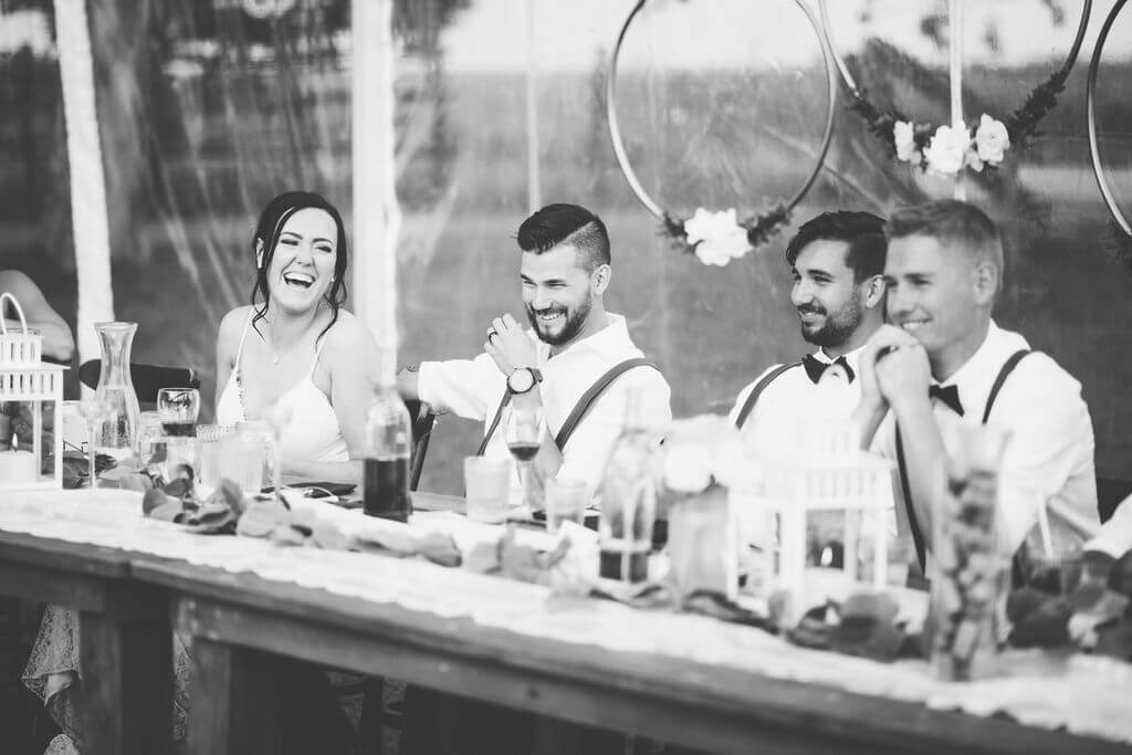 black and white photo of bridal party laughing during speeches