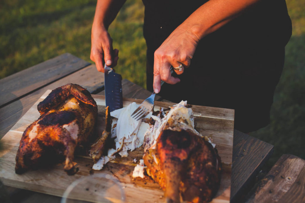 cutting a beautiful roast chicken in a picnic setting 
