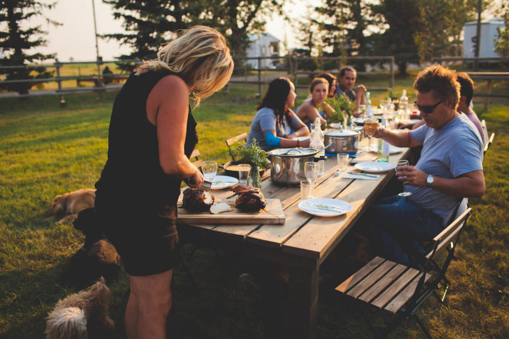 family gathering around a dinner table in a open prairie field 