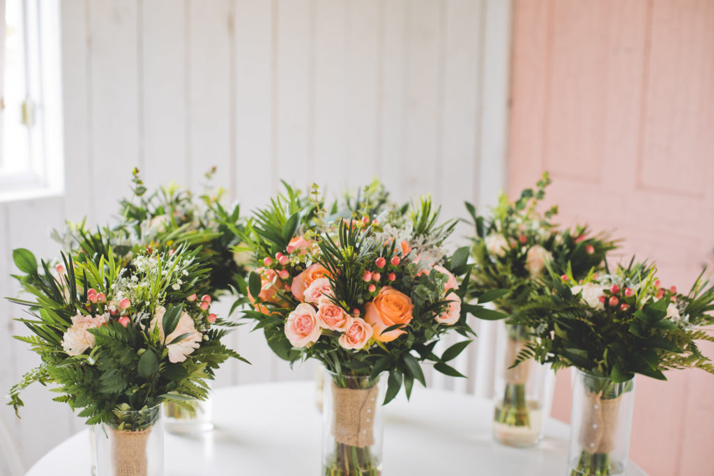 coral and peach toned flower bouquets add a vibrant flair to this outdoor prairie wedding on a rainy day in Alberta, Canada.