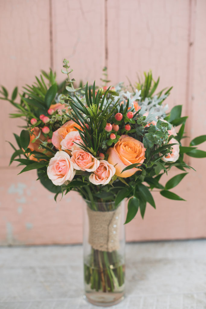 vibrant coral and peach toned bridal bouquet with bold greenery to add flair to this outdoor wedding - vanessa and josh, the gathered