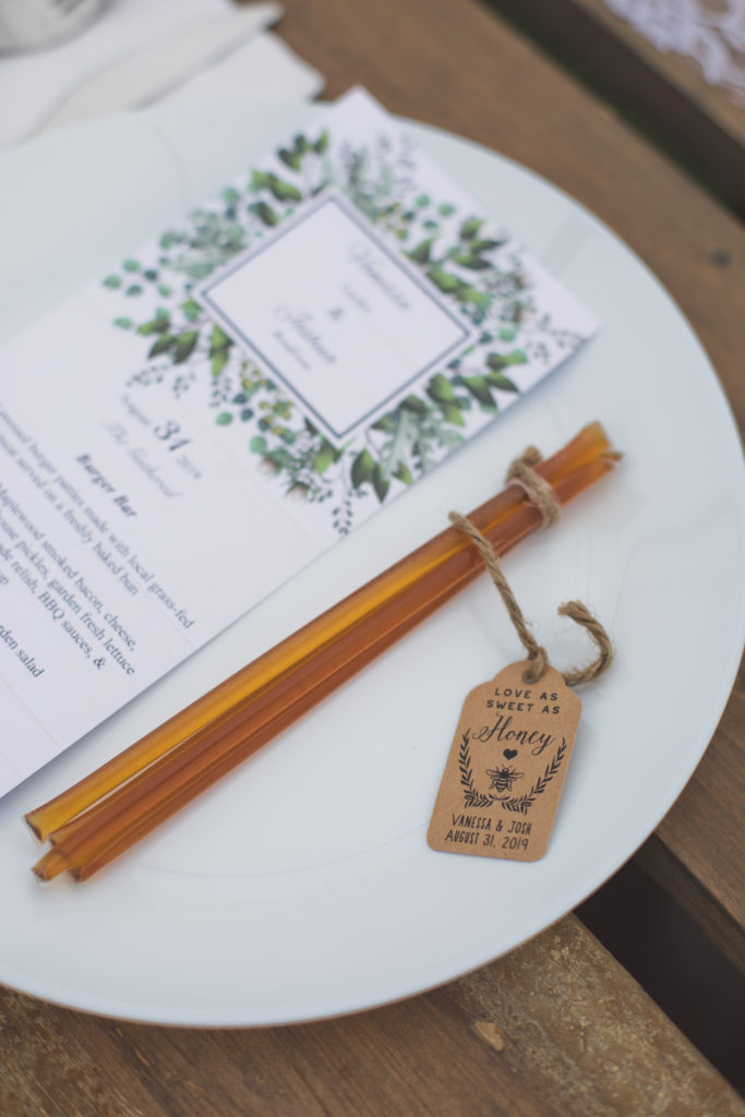 honey sticks make the best favours for your wedding guests, here they are placed on a white plate beside a menu. Outdoors weddings ideas.