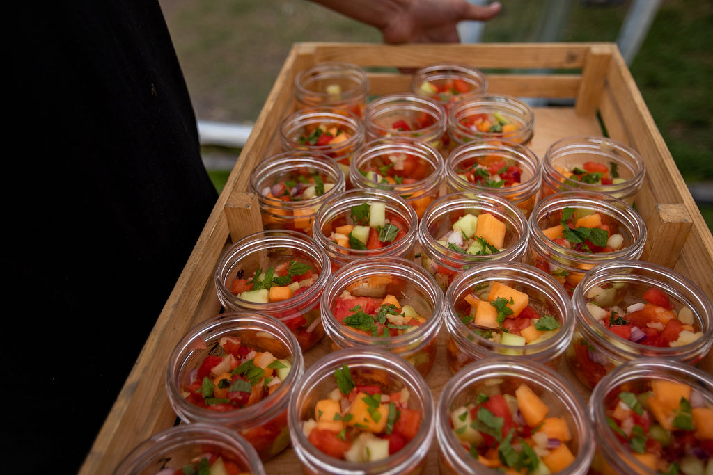 mini masons jars lines a tray with melon fruit salad filling them. The perfect backyard wedding salad.