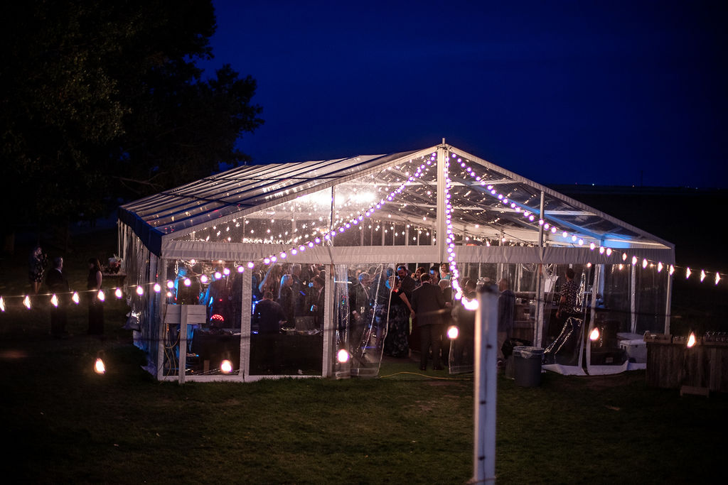 clear tent at night with warm globe lights illuminating the night sky at this Calgary, Alberta wedding venue. www.thegathered.ca