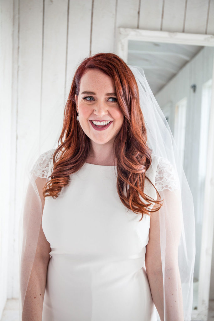 bride with beautiful red hair and a veil celebrates her day in a white cottage