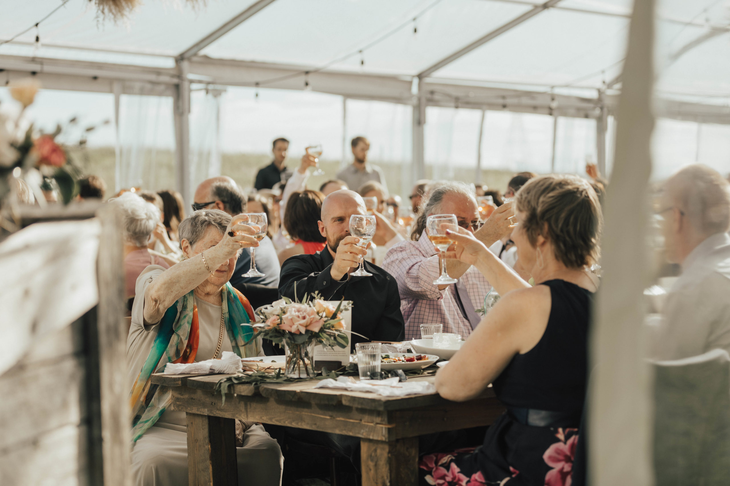 wedding guests hold up their wine glasses as their cheer to a wedding toast