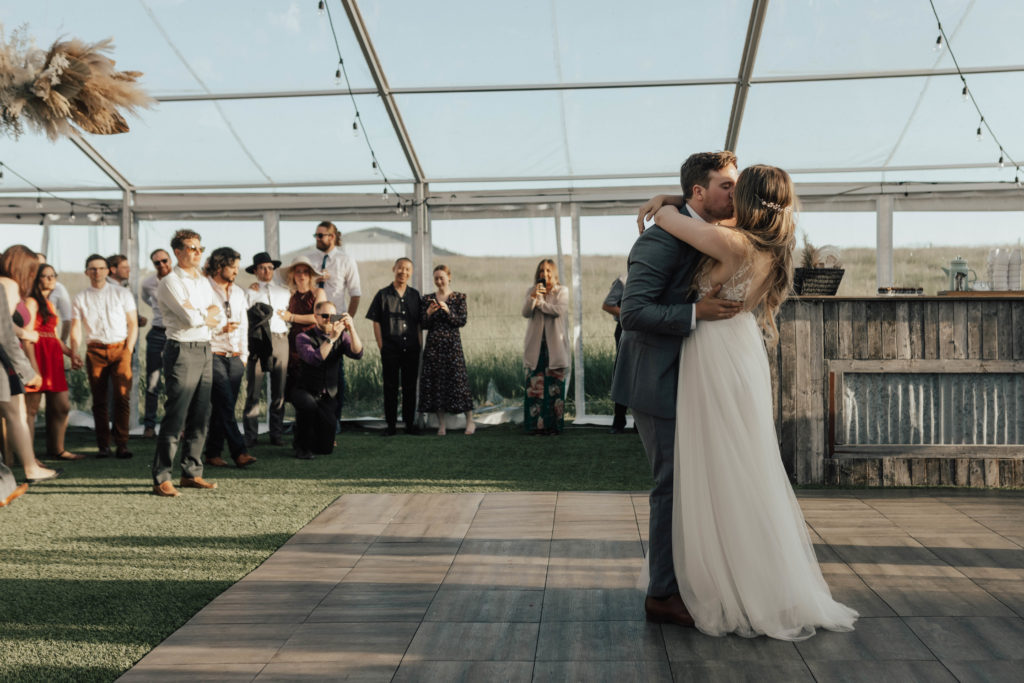 First dance in a clear tent, weddings guests watch from the sides as the sun sets at this outdoor wedding. The Gathered, Calgary Alberta
