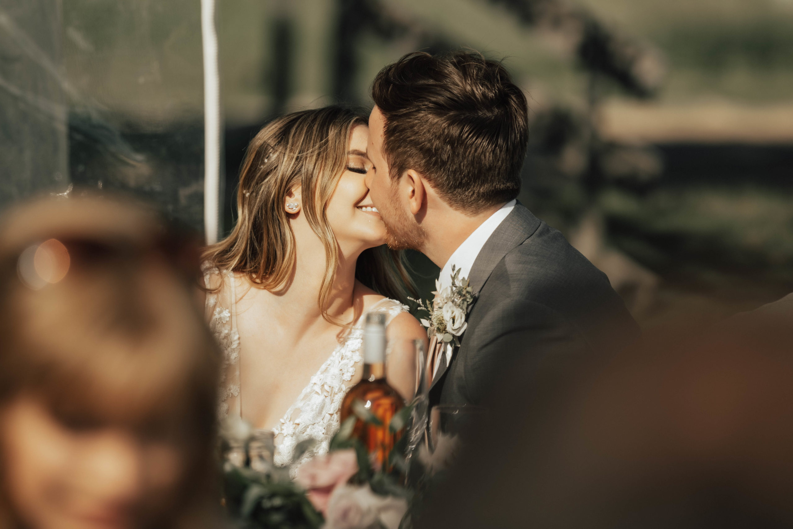 couple kisses at their head table of an outdoor wedding