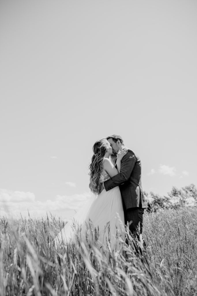 black and white image of a couple kissing in a wheat field.