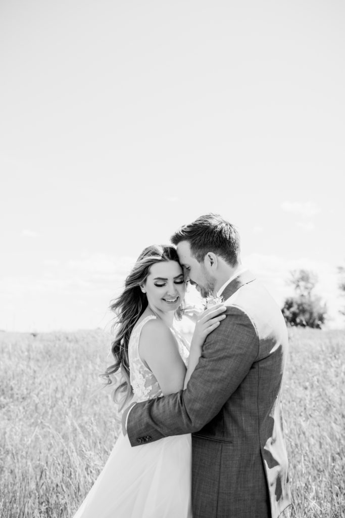 black and white image of bride and groom - brides long curling hair and modern dress makes for a romantic photo.