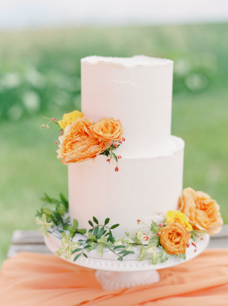 two layered cake with white frosting and orange flowers decorating the cake