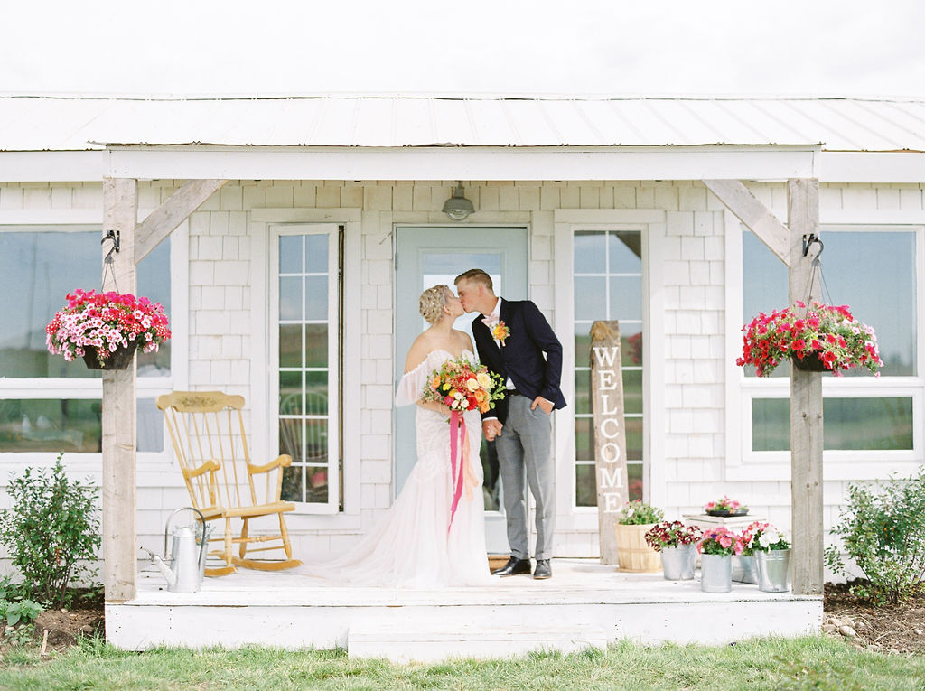 bright pink flowers accentuate a white bridal cottage on the gathered farm in alberta, canada