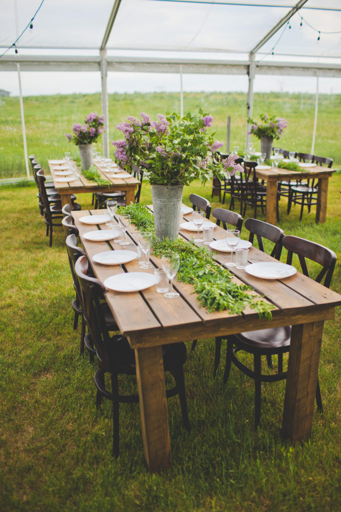 wood crossback tables and chairs at an outdoor wedding in the prairies with lilac flowers in galvanized buckets. www.thegathered.ca