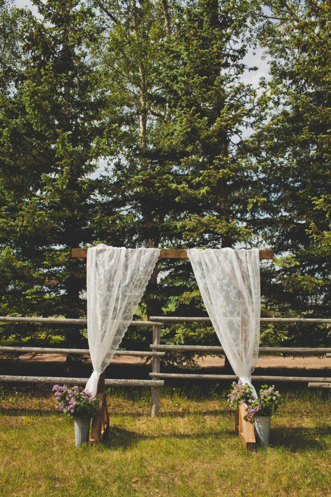 arbor decorated with white lace curtains and galvanized buckets with lilacs inside.