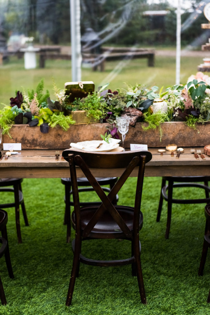 wood box filled with plants and greenery with a wood table and chairs