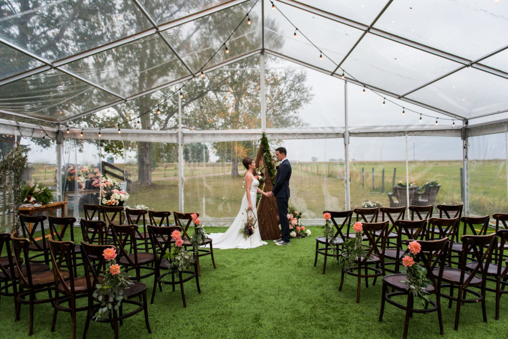 inside a clear tent a unique triangle arbor makes for a unique focal point at this intimate ceremony in Alberta