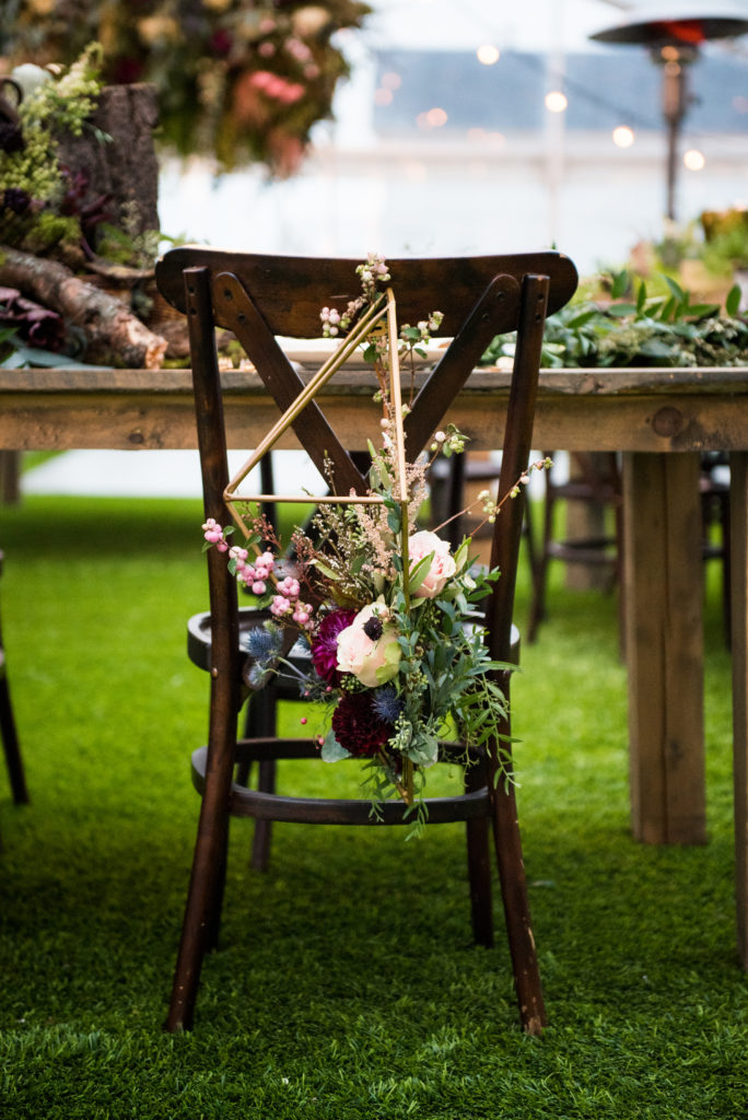 a wooden chair with wild flowers hanging off of it