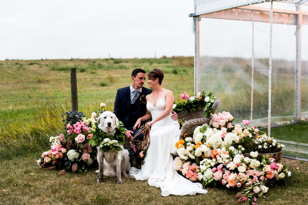 dogs in flowers is the cutest thing ever. This couple poses beside a dog surrounded by flowers.