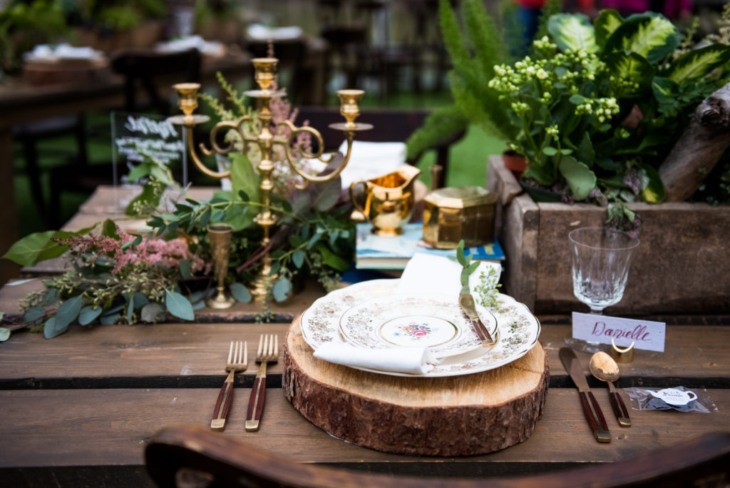 table setting filled with greenery, candelabra, flowers and china with gold flatware the perfect wild eco friendly styled shoot