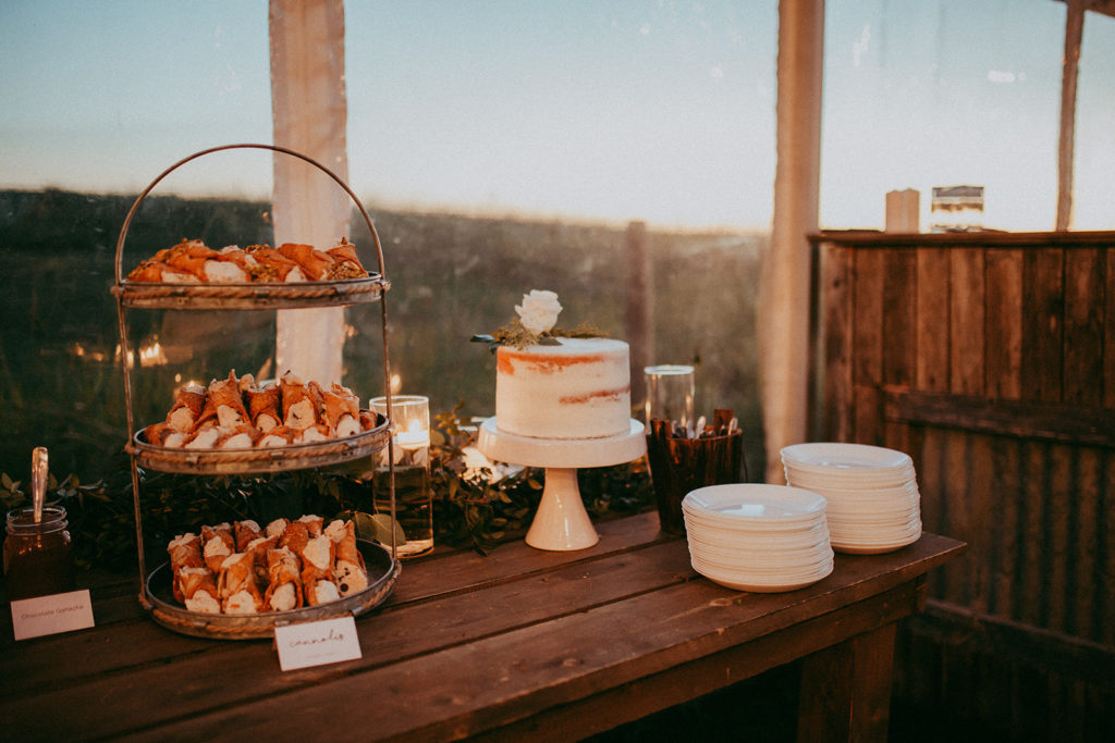 wedding dessert table with a white naked cake and a 3 tiered tray of cannelloni's