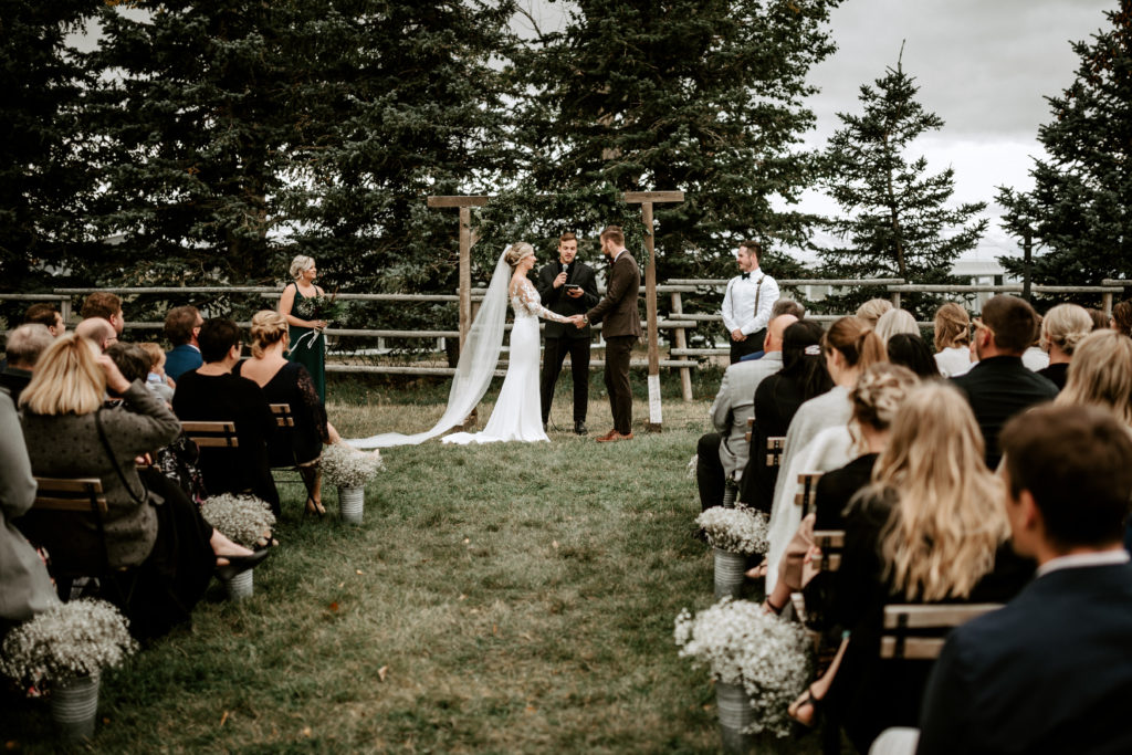 outdoor ceremony surrounded by pine trees and a wooden arbor.